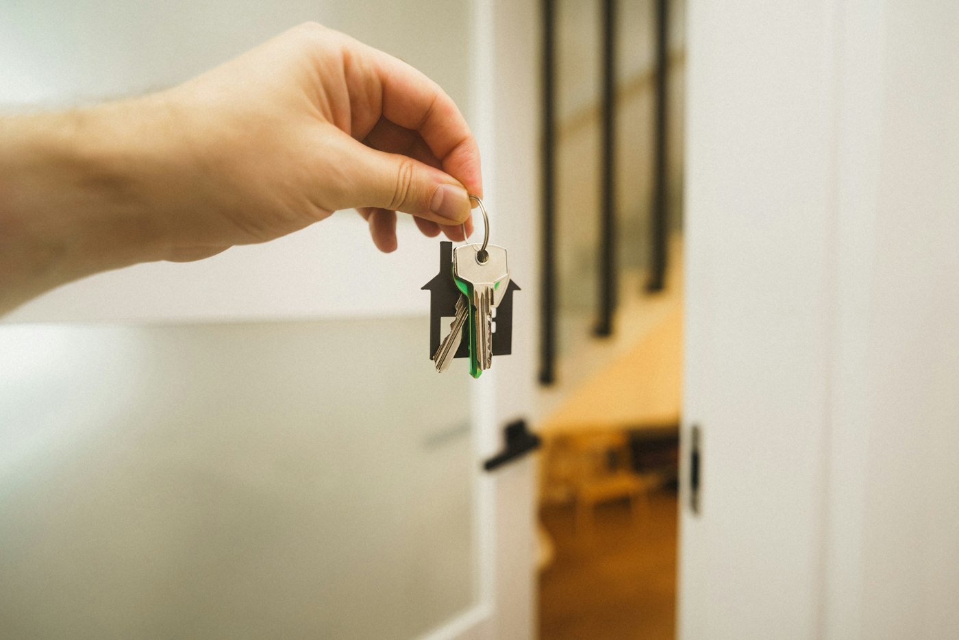 A hand holding a set of house keys in a bright hallway